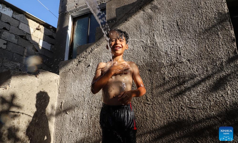 A Palestinian boy is poured with water to cool off during hot weather in Gaza City, on July 17, 2023.(Photo: Xinhua)