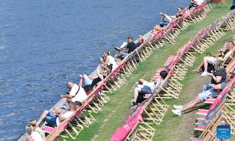 People sit by a river in Berlin, Germany, on July 13, 2023.(Photo: Xinhua)