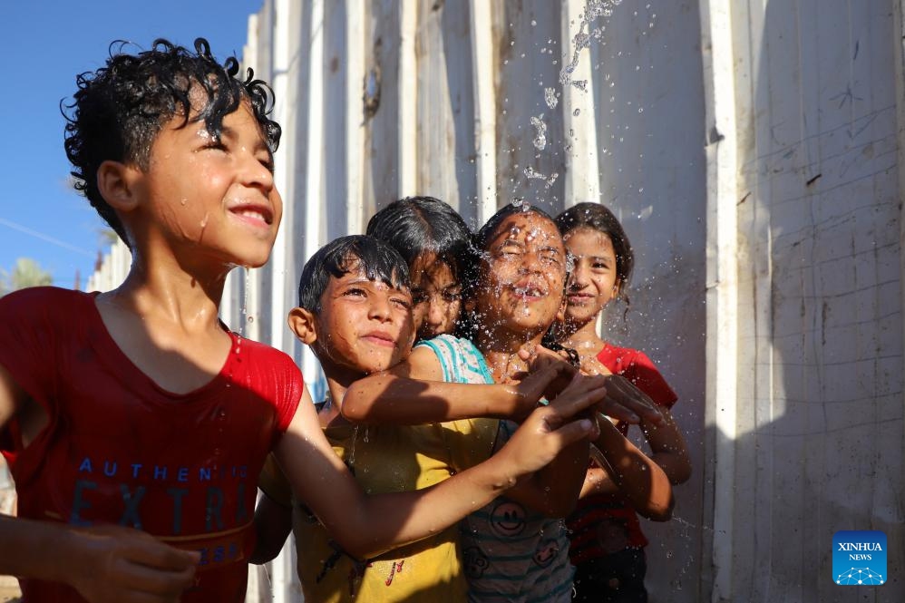Palestinian children are poured with water to cool off during hot weather in Gaza City, on July 17, 2023.(Photo: Xinhua)