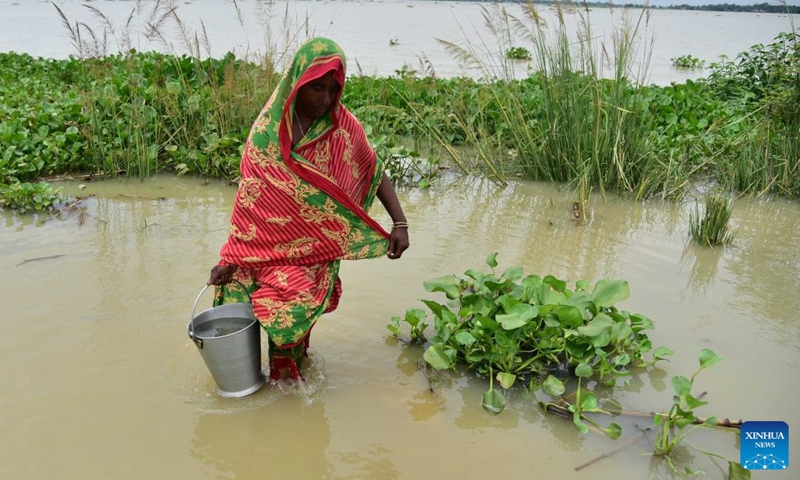 A woman fetches drinking water in a flood-affected area in Morigaon district of India's northeastern state of Assam, July 16, 2023. (Str/Xinhua)