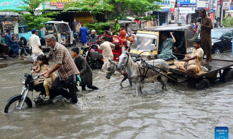 Commuters wade through a flooded road after heavy monsoon rain in southern Pakistan's Hyderabad, July 23, 2023. (Str/Xinhua)