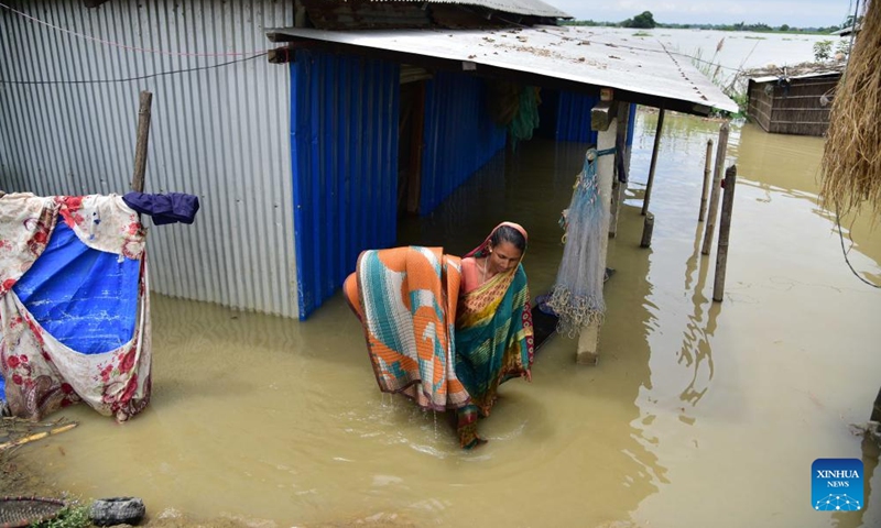 A woman moves her belongings outside her waterlogged shanty at a flood-affected area in Morigaon district of India's northeastern state of Assam, July 16, 2023. (Str/Xinhua)