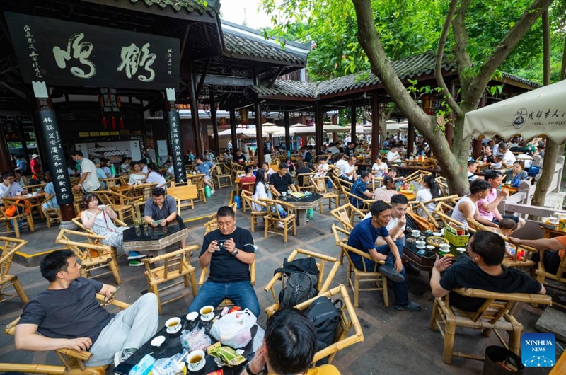 People enjoy tea at an open tea house in Chengdu of southwest China's Sichuan Province, on June 30, 2021. The 31st FISU Summer World University Games is scheduled to take place in Chengdu from July 28 to August 8, 2023. (Xinhua/Shen Bohan)