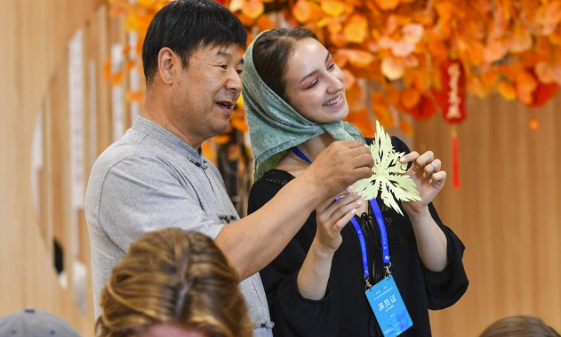 Sofia (R) presents her paper-cutting work at the Xinjiang Library in Urumqi, capital of northwest China's Xinjiang Uygur Autonomous Region, on July 23, 2023. This is an unforgettable tour of Xinjiang - wondrous! said Sofia Maksimovna Efremenko, a young Russian dancer who has spent a pleasant week here.

A member of the song and dance ensemble Zorenka of Balashov City, Saratov Oblast of Russia, Sofia came along with more than 1,000 of her counterparts from Asia, Europe and Africa for the 6th China Xinjiang International Dance Festival being held from July 20 to Aug. 5.

Besides their performance on stage, Sofia and her colleagues visited places of interest in Urumqi for a profound experience of the Chinese culture, particularly the traditions in Xinjiang. I'll definitely come again. (Xinhua/Hu Huhu)