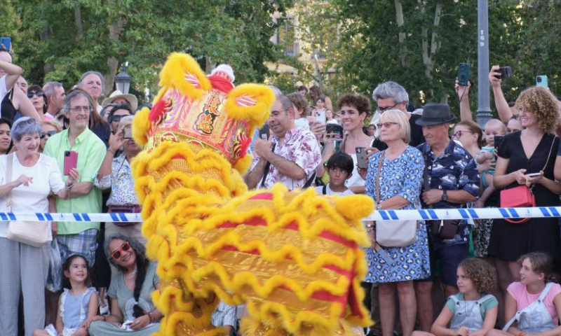 People watch lion dance at the Plaza de Oriente (Eastern Plaza) in Madrid, Spain, on Aug. 5, 2023. The Shenzhen Fuyong Huaide Lion Dance Troupe performed on the streets of Madrid from Friday to Sunday at the invitation of the Madrid Summer in the City Festival and the Chinese Cultural Center in Madrid. (Xinhua/Meng Dingbo)