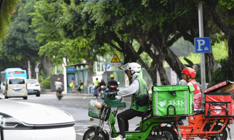 Deliverymen are seen on a street in Fuzhou, southeast China's Fujian Province, July 30, 2023. Fuzhou has seen its urban life gradually back to normal after typhoon Doksuri swept through the city. (Xinhua/Wei Peiquan)