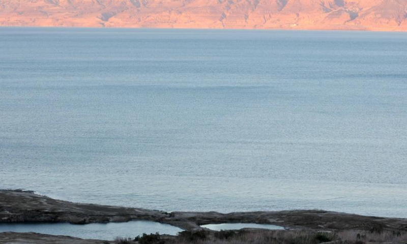 People visit sinkholes on the shore of the Dead Sea near Ein Gedi beach, Israel on Aug. 6, 2023. Statistics showed that the Dead Sea had been shrinking at an alarming pace, its water level dropping by 1.2 meters each year. As the water receded, a barren landscape of salt rock and numerous sinkholes appeared. (Photo by Gil Cohen Magen/Xinhua)