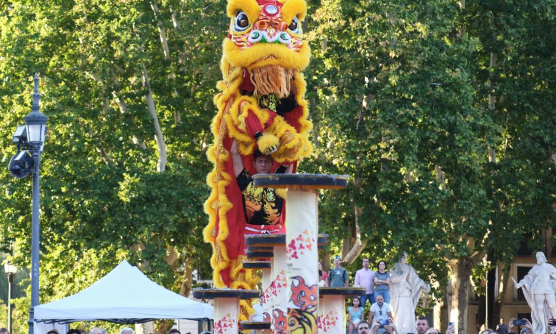 Actors perform lion dance at the Plaza de Oriente (Eastern Plaza) in Madrid, Spain, on Aug. 5, 2023. The Shenzhen Fuyong Huaide Lion Dance Troupe performed on the streets of Madrid from Friday to Sunday at the invitation of the Madrid Summer in the City Festival and the Chinese Cultural Center in Madrid. (Xinhua/Meng Dingbo)