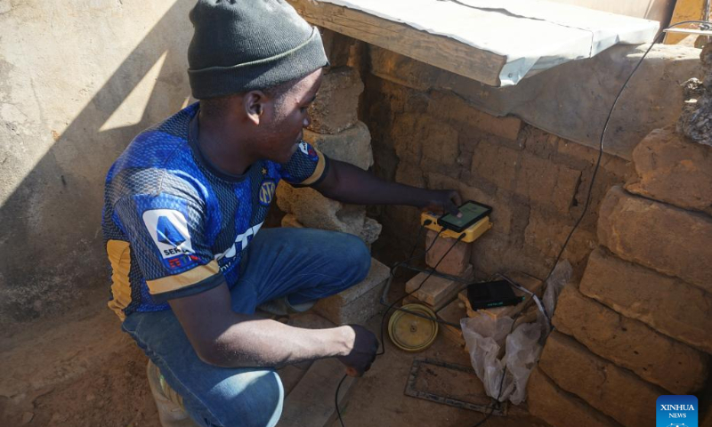 A man charges his phone using solar powered equipment in Chibombo district, central Zambia, July 24, 2023. (Photo by Lillian Banda/Xinhua)