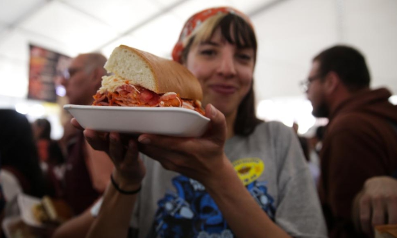 A woman shows a torta during the 18th annual Torta Fair in Mexico City, capital of Mexico, Aug. 2, 2023. Torta is known as a traditional sandwich in Mexico and is welcomed by local people. (Photo: Xinhua)