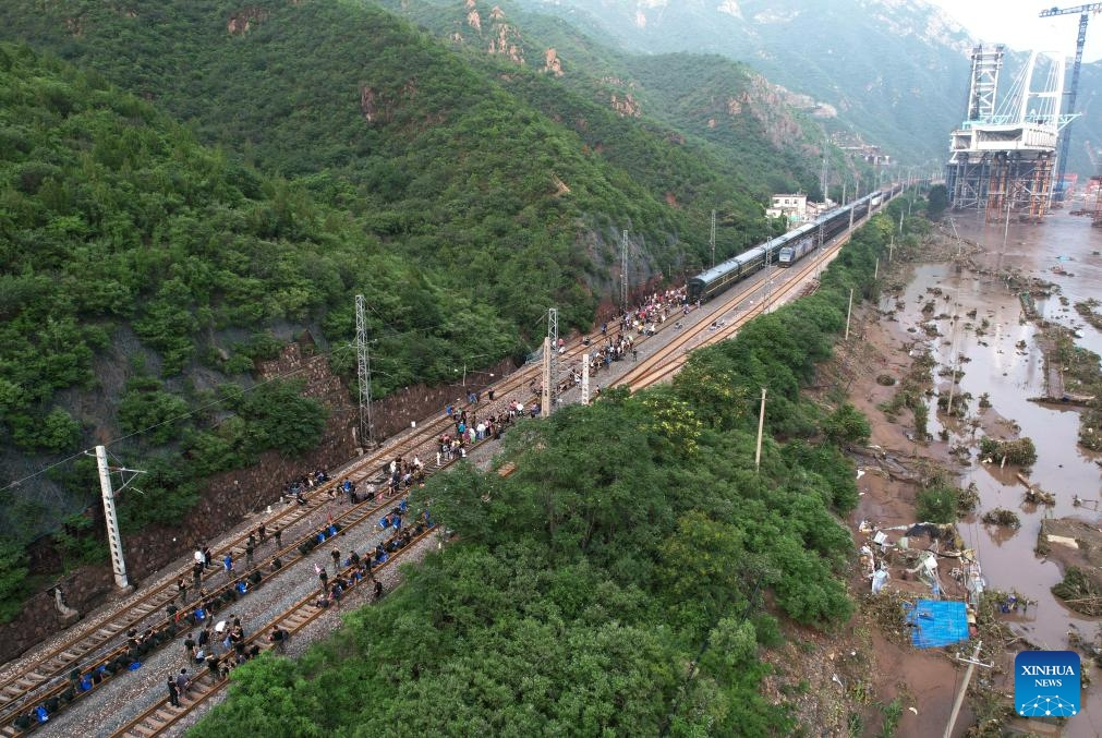 This aerial photo taken on Aug. 2, 2023 shows stranded passengers walking to the transshipment train with the help of rescuers in Mentougou District of Beijing, capital of China. The last batch of stranded passengers of trains Z180 and K396 arrived at the Fengtai Railway Station in Beijing early in the morning on Aug. 3. (Photo: Xinhua)