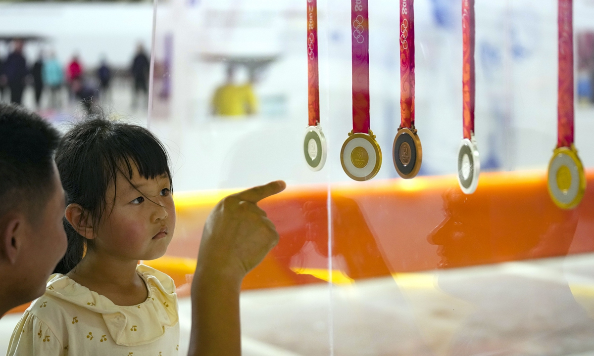 A man shows a girl the medals of the Beijing 2008 Olympics on August 8, 2023 at an exhibition to mark the 15th anniversary of the event.
