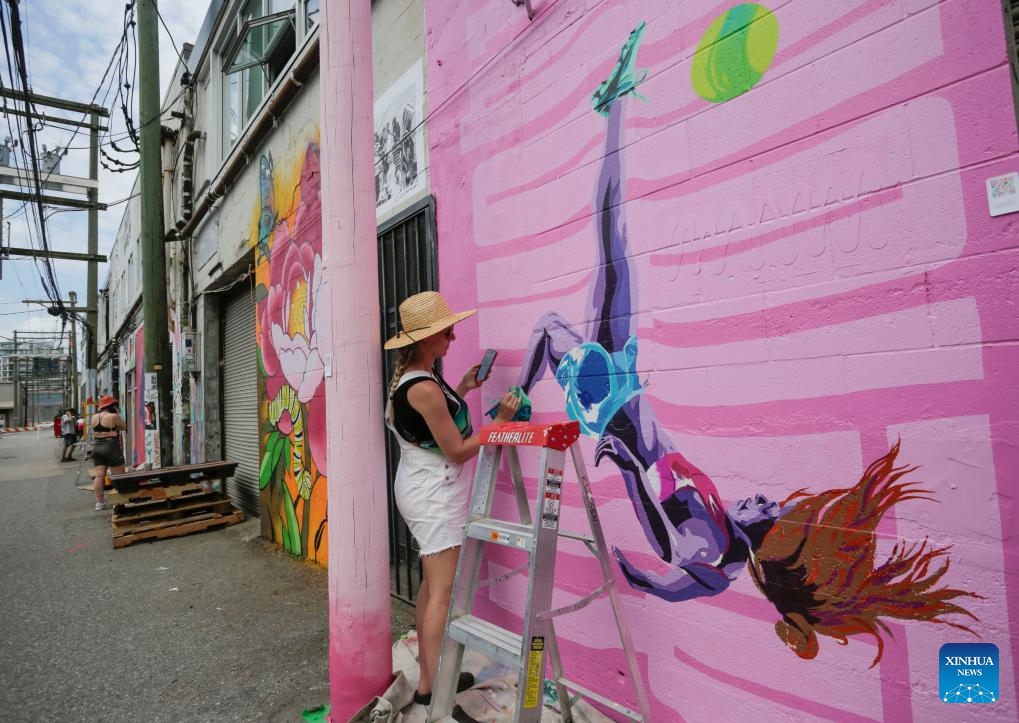 An artist works on her mural during the annual Vancouver Mural Festival in Vancouver, British Columbia, Canada, on Aug. 7, 2023. Mural artists from across the world participated in the annual ten-day festival, turning the urban space into an art gallery.(Photo: Xinhua)