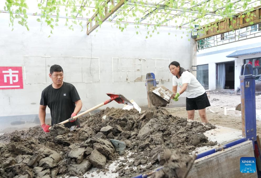 Villagers clean up slit in their yard in Xiazhuang Village, Sanpo Town, Laishui County, in north China's Hebei Province, Aug. 8, 2023. Affected by Typhoon Doksuri, Laishui County suffered heavy rainfall recently and some villages encountered traffic and communication disruptions. At present, the local authorities are mending infrastructure damaged by flood to bring life back to normal as soon as possible.(Photo: Xinhua)