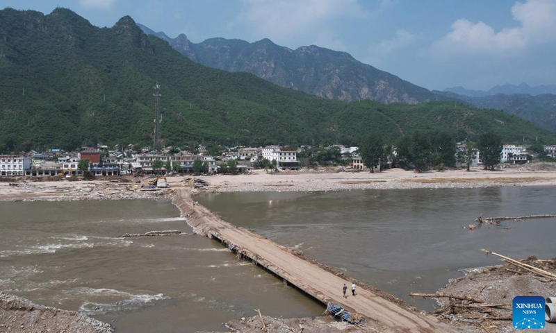 This aerial photo taken on Aug. 9, 2023 shows villagers walking on a bridge leading to Shangzhuang Village of Sanpo Town, Laishui County, north China's Hebei Province. Some roads blocked by the rain-triggered floods in the county are repaired, and electricity and communication services are restored.(Photo: Xinhua)