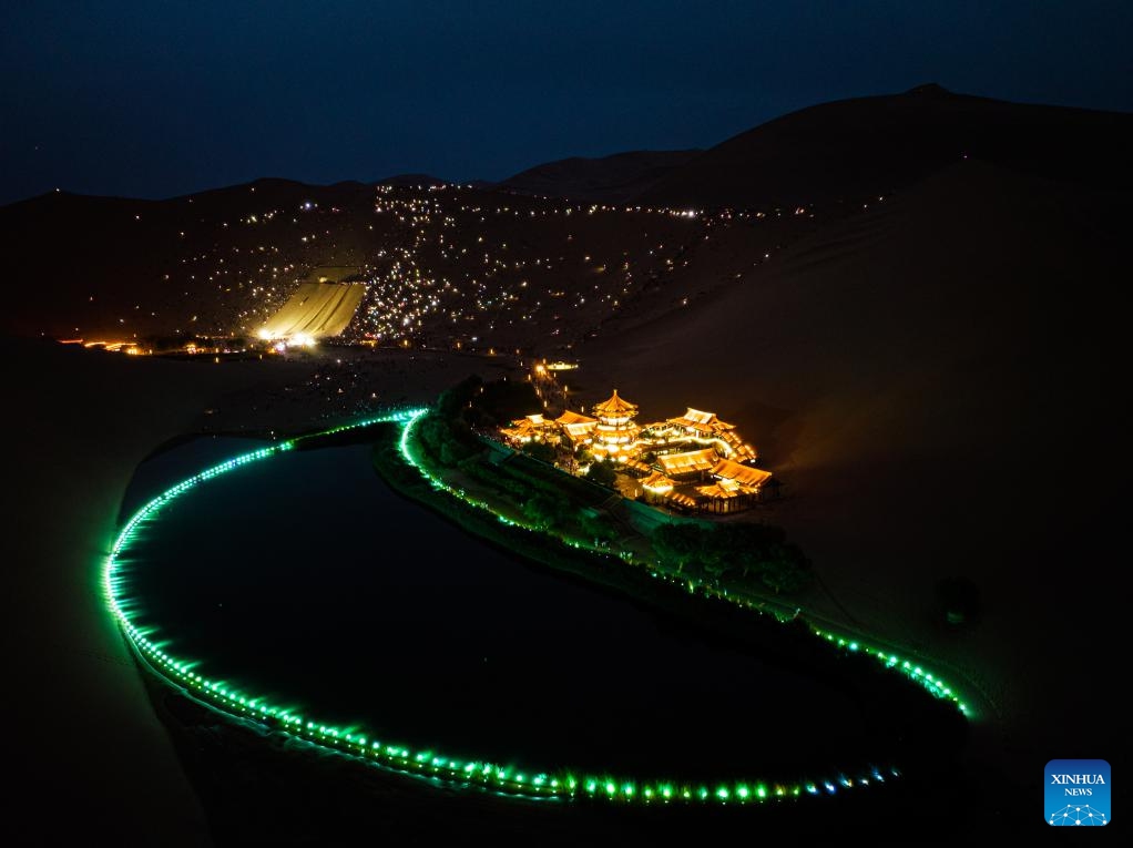 This aerial photo taken on Aug. 8, 2023 shows tourists attending a live concert with their mobile phone flashlights turned on at the Mingsha Mountain and Crescent Spring scenic spot in Dunhuang, northwest China's Gansu Province. The Mingsha Mountain and Crescent Spring scenic spot in Dunhuang has entered its peak tourist season during the summer vacation.(Photo: Xinhua)