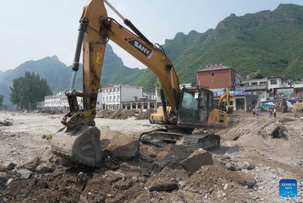 This aerial photo taken on Aug. 9, 2023 shows a worker operating machinery to repair a road leading to Shangzhuang Village of Sanpo Town, Laishui County, north China's Hebei Province. Some roads blocked by the rain-triggered floods in the county are repaired, and electricity and communication services are restored.(Photo: Xinhua)