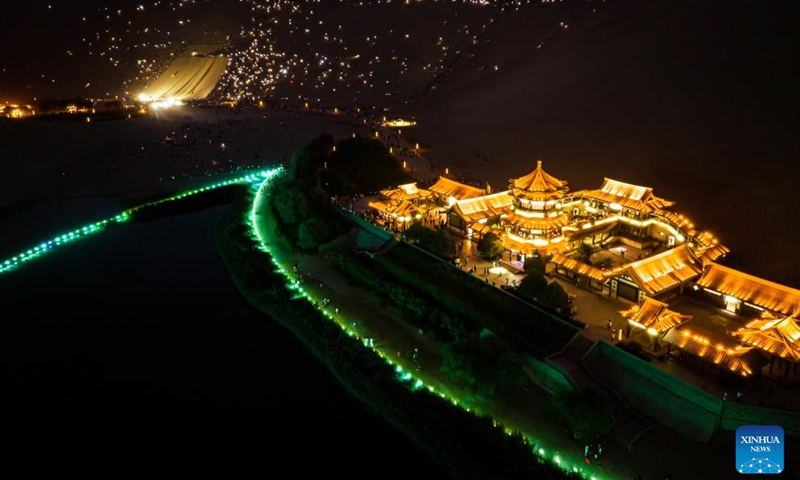 This aerial photo taken on Aug. 8, 2023 shows tourists attending a live concert with their mobile phone flashlights turned on at the Mingsha Mountain and Crescent Spring scenic spot in Dunhuang, northwest China's Gansu Province. The Mingsha Mountain and Crescent Spring scenic spot in Dunhuang has entered its peak tourist season during the summer vacation.(Photo: Xinhua)