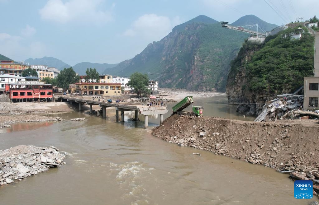 This aerial photo taken on Aug. 9, 2023 shows workers operating machinery to repair a bridge in Sanpo Town, Laishui County, north China's Hebei Province. Some roads blocked by the rain-triggered floods in the county are repaired, and electricity and communication services are restored.(Photo: Xinhua)