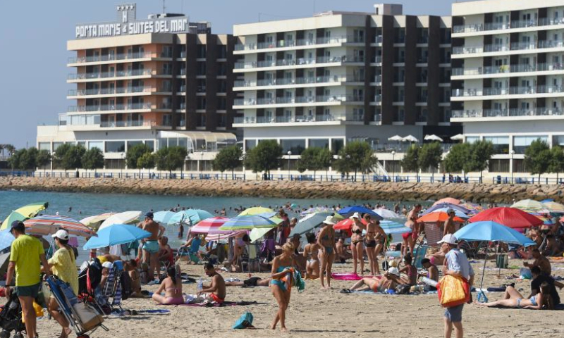 People enjoy their leisure time on a beach in Alicante, Spain, Aug. 11, 2023. (Photo by Gustavo Valiente/Xinhua)