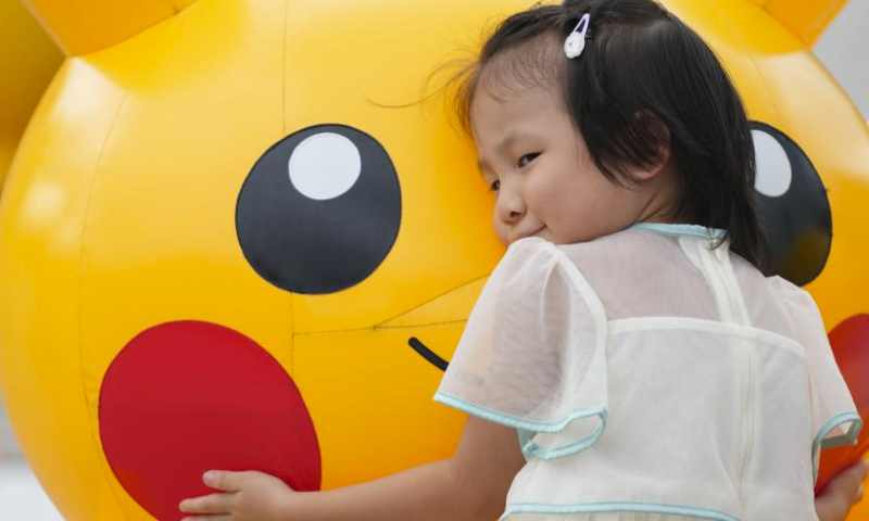 A girl hugs an inflatable Pikachu at Minatomirai in Yokohama, Japan, Aug. 13, 2023. To commemorate the launch of the 2023 Pokemon World Championships, a Pokemon festival is held in Yokohama's Minatomirai from Aug.11 to Aug.14. (Xinhua/Zhang Xiaoyu)