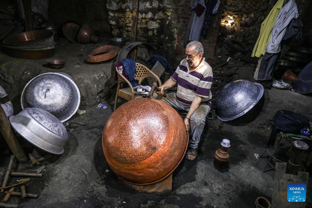 A coppersmith makes a vessel at a workshop in Cairo, Egypt, on Aug. 13, 2023.(Photo: Xinhua)