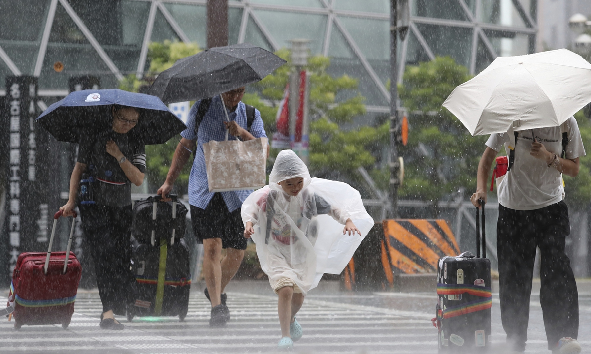 People walk on a street while Typhoon No.7, called Lan, landing the main island of Japan in Nagoya, Aichi Prefecture on August 15, 2023. The railways and commercial facilities in various parts of the Kinki region have decided to suspend or close operations. Photo: VCG