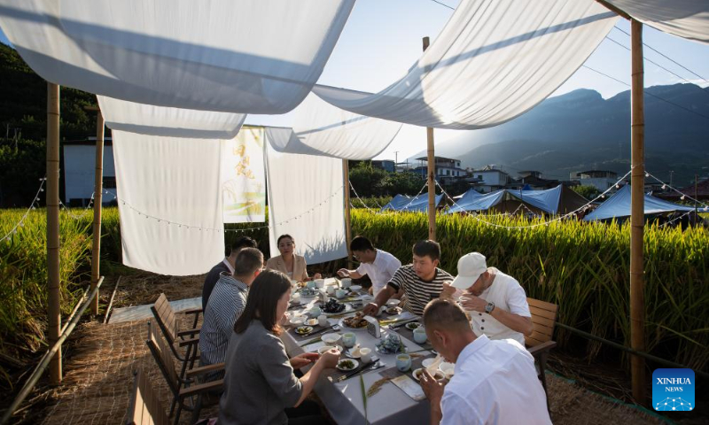 This photo taken on Sept. 2, 2023 shows people having traditional local food in Xinglong Village, Yanbian County of southwest China's Sichuan Province. (Xinhua/Jiang Hongjing)