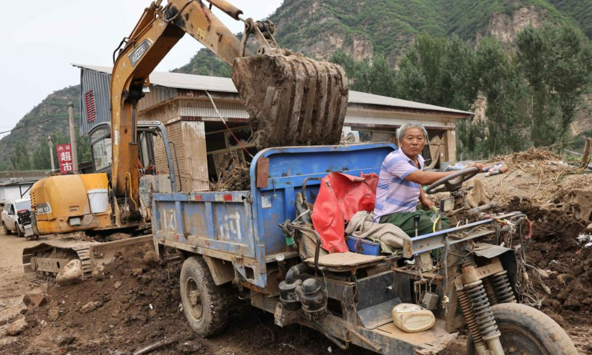 Villager Zhang Chengshan drives a tractor to transfer silt at Pingyu Village of Laishui County, north China's Hebei Province, Aug 17, 2023. Laishui County has suffered heavy rainfall due to the impact of Typhoon Doksuri recently. Photo:Xinhua