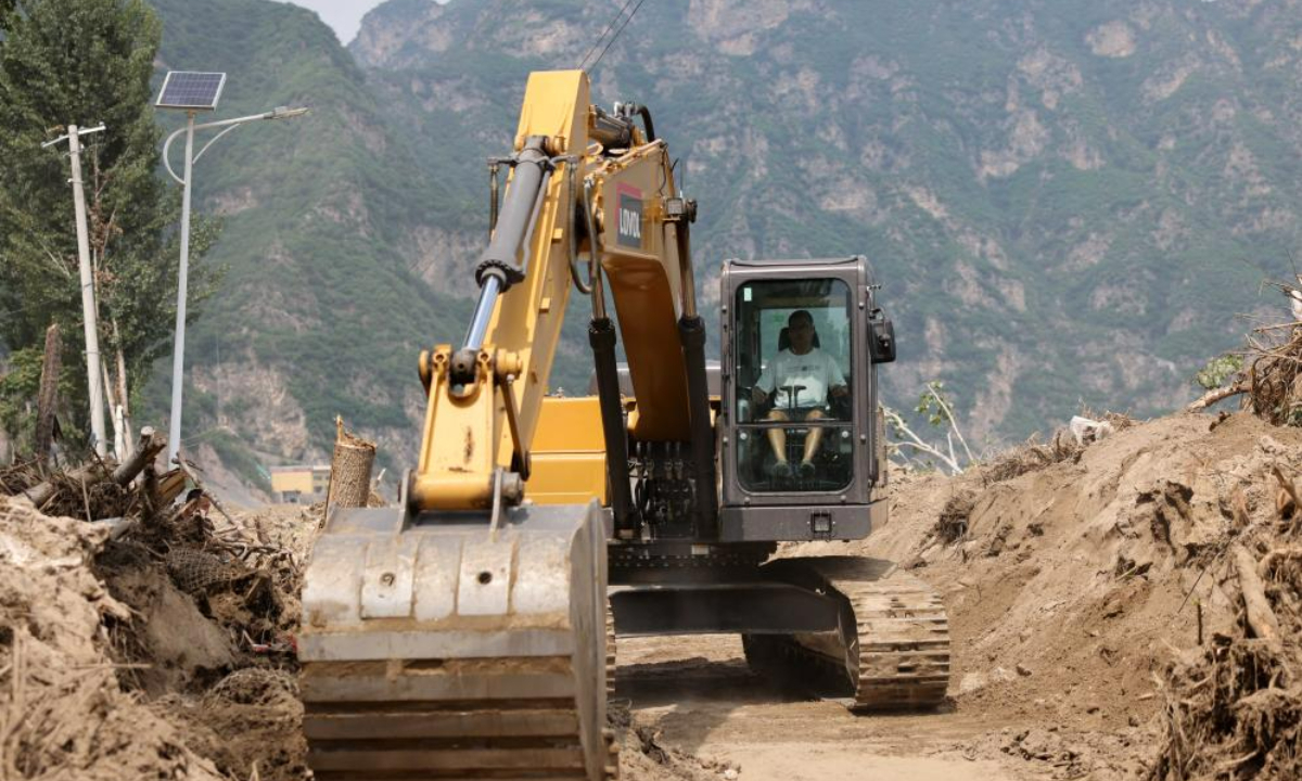 A worker drives an excavator to clean up a road at Pingyu Village of Laishui County, north China's Hebei Province, Aug 17, 2023. Laishui County has suffered heavy rainfall due to the impact of Typhoon Doksuri recently. Photo:Xinhua