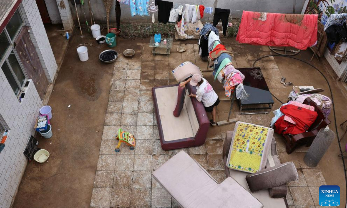 Villager Zhao Guojin cleans up furniture in her yard at Pingyu Village of Laishui County, north China's Hebei Province, Aug 17, 2023. Laishui County has suffered heavy rainfall due to the impact of Typhoon Doksuri recently. Photo:Xinhua