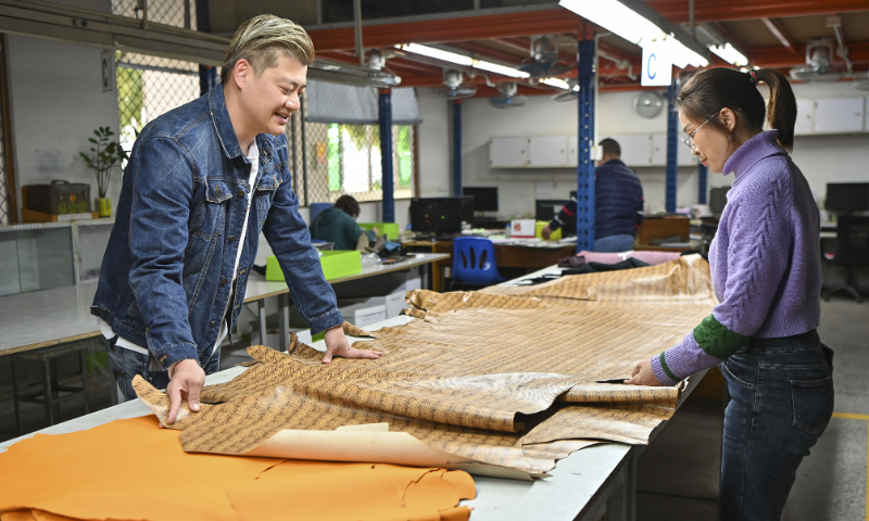 Wang Boyang (left), a young man from Taiwan inspects a type of leather material with the staff in his factory in Huizhou, Guangdong Province on March 1, 2023. Photo: VCG