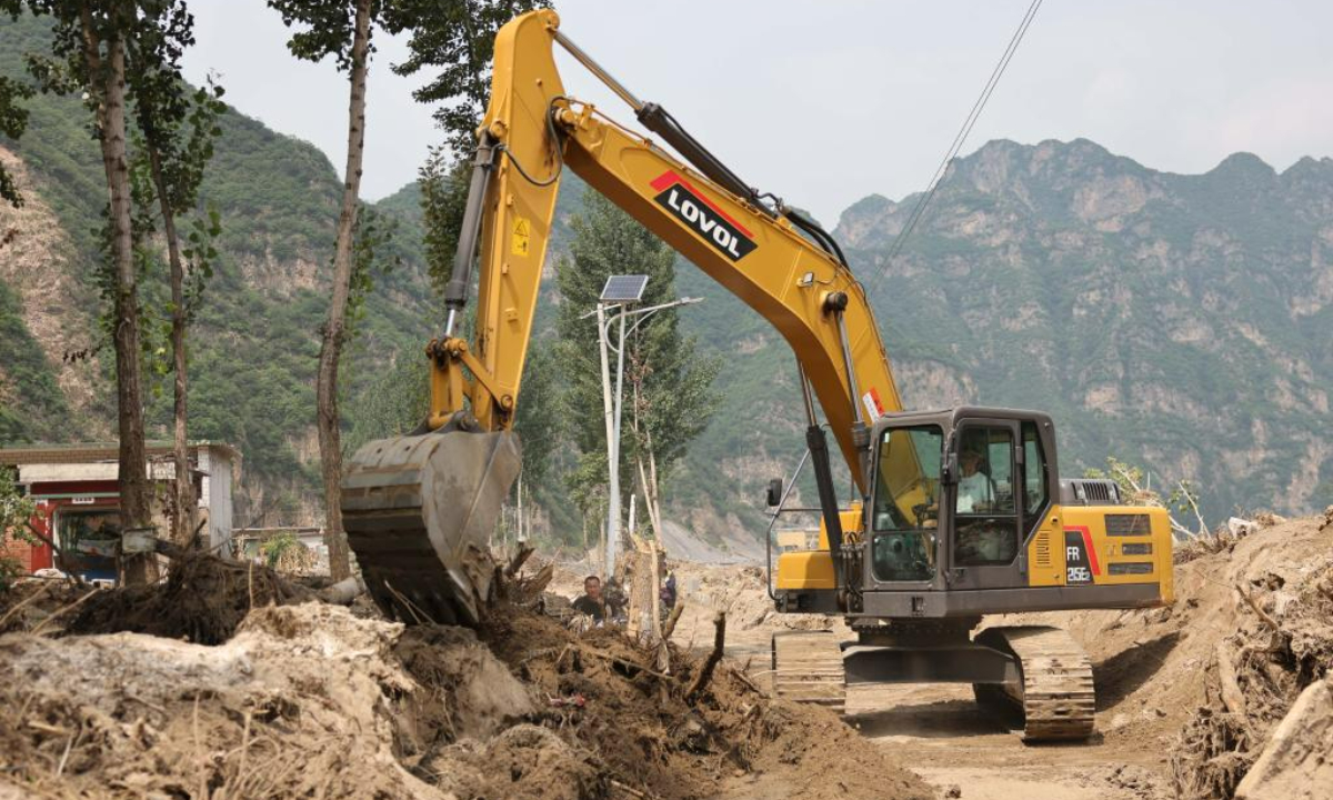 A worker drives an excavator to clean up a road at Pingyu Village of Laishui County, north China's Hebei Province, Aug 17, 2023. Laishui County has suffered heavy rainfall due to the impact of Typhoon Doksuri recently. Photo:Xinhua