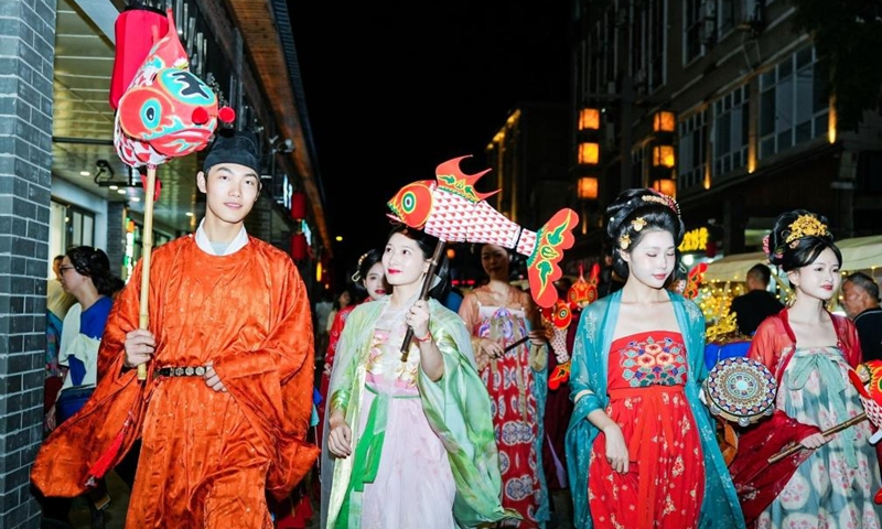 Tourists dressed in Chinese traditional clothes visit a street during a cultural festival in Changhua Town of Hangzhou City, east China's Zhejiang Province, Aug. 18, 2023. The cultural festival, which kicked off Friday in Changhua Town, aimed to boost the nighttime economy by presenting the culture of Tang (618-907) and Song (960-1279) Dynasties and promoting local snacks and scenic spots. (Xinhua/Xu Yu)