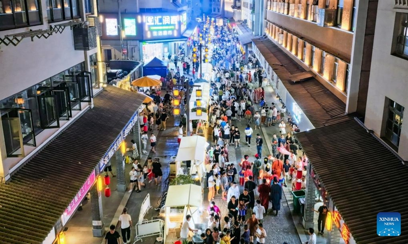 This aerial photo taken on Aug. 18, 2023 shows tourists visiting a street during a cultural festival in Changhua Town of Hangzhou City, east China's Zhejiang Province. The cultural festival, which kicked off Friday in Changhua Town, aimed to boost the nighttime economy by presenting the culture of Tang (618-907) and Song (960-1279) Dynasties and promoting local snacks and scenic spots. (Xinhua/Xu Yu)