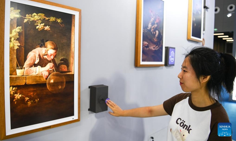 A visitor tries a digital device to interact with a painting in the digital culture exhibition area at the 10th West China Culture Industries Expo in Xi'an, northwest China's Shaanxi Province, Aug. 18, 2023. The 10th West China Culture Industries Expo opened on Thursday in Xi'an and will last till Aug. 20. Photo: Xinhua