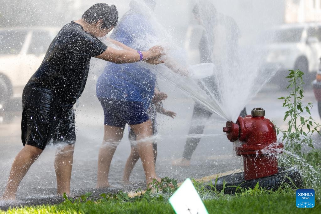 Kids and adults cool off beside an open fire hydrant in the New City neighborhood on the southwest side of Chicago, the United States, on Aug. 23, 2023. The temperature at O'Hare International Airport in Chicago, the third most populous city in the United States, reached 98 degrees Fahrenheit (36.67 degrees Celsius) Wednesday afternoon, breaking the city's previous daily high temperature record for Aug. 23 of 97 degrees Fahrenheit (36.11 degrees Celsius), according to the U.S. National Weather Service.(Photo: Xinhua)