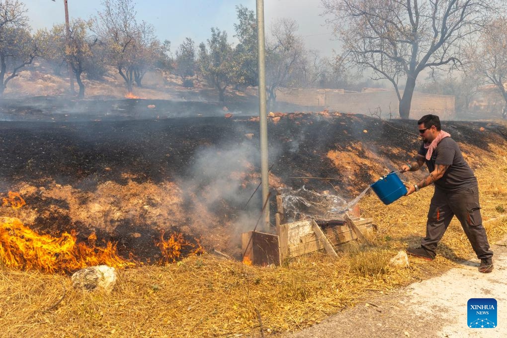 A volunteer tries to extinguish a wildfire in Hasia village, near Athens, Greece, on Aug. 22, 2023. Wildfires, erupted on Tuesday near the Greek capital, forced the evacuation of settlements and the closure of roads.(Photo: Xinhua)