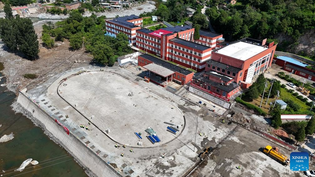 This aerial photo taken on Aug. 23, 2023 shows construction workers on the playground at the Xiayunling central primary school in Fangshan District of Beijing, capital of China. Due to the influence of heavy rainfall, Xiayunling central primary school in Fangshan District of Beijing had part of its buildings and playground collapsed, and the road and bridge in front of the school damaged.(Photo: Xinhua)