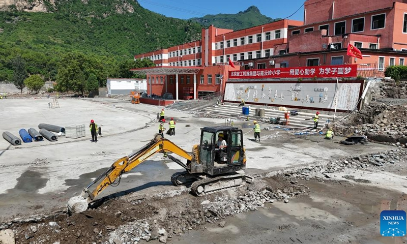 This aerial photo taken on Aug. 23, 2023 shows construction workers on the playground at the Xiayunling central primary school in Fangshan District of Beijing, capital of China. Due to the influence of heavy rainfall, Xiayunling central primary school in Fangshan District of Beijing had part of its buildings and playground collapsed, and the road and bridge in front of the school damaged.(Photo: Xinhua)