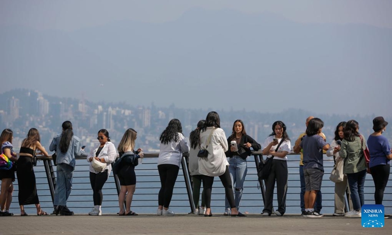 People gather at the waterfront in haze in downtown Vancouver, British Columbia, Canada, Aug. 26, 2023. The Metro Vancouver continued an air quality advisory for the metro Vancouver region on Saturday due to high concentration of fine particulate matter caused by smoke from wildfires spreading across British Columbia. Photo: Xinhua