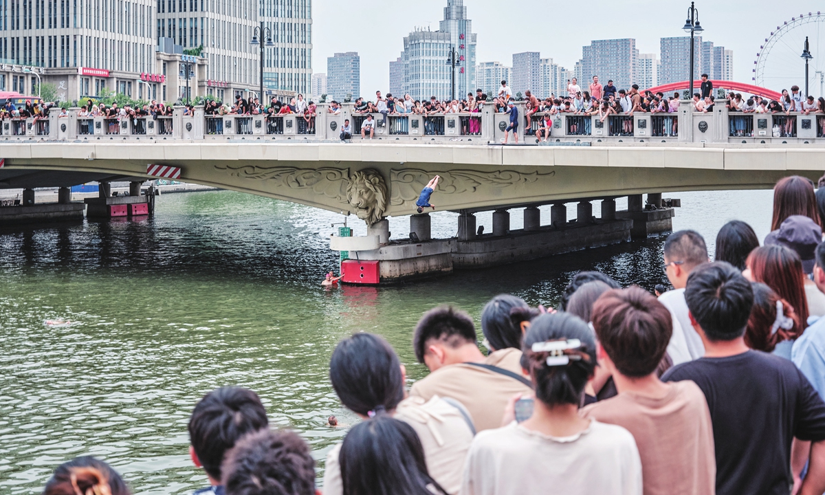 Visitors watch elders dive from a bridge in North China's Tianjin Municipality on August 28, 2023. As an increasing number of elders perform synchronized diving at the site, it has become a hotspot for visitors. China's summer travel market is expected to surpass the same period in 2019, with 1.3 billion domestic trips estimated to be made in the July-August period. Photo: VCG