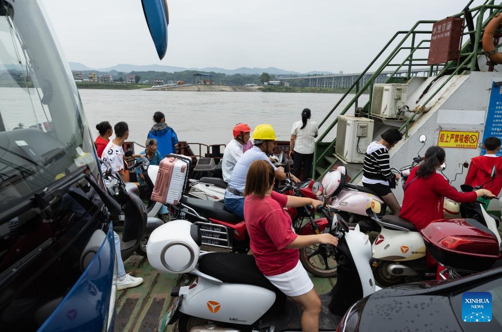 Vehicles and passengers take the cross-river vehicle ferry linking Nixi Town and Juexi Town in Xuzhou District of Yibin, southwest China's Sichuan Province, Aug. 28, 2023. The cross-river vehicle ferry service that links Nixi Town and Juexi Town in Xuzhou District of Yibin started in May of 1992. This ferry service has been one of the most important transportation methods for local people living nearby on both sides of Minjiang River.(Photo: Xinhua)