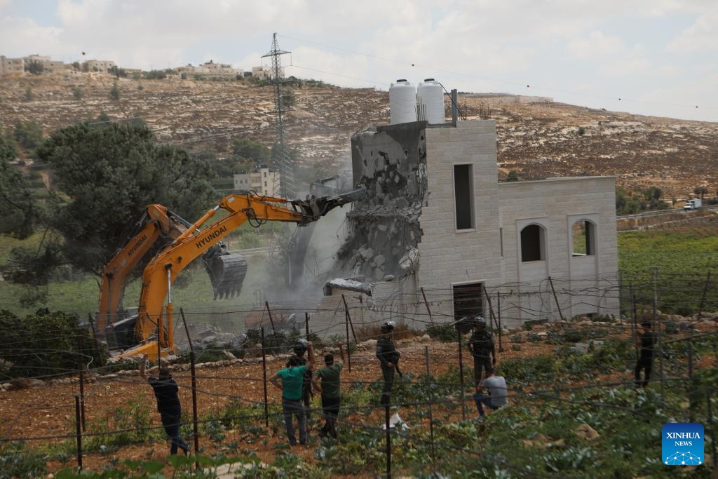 Israeli security forces stand guard as an Israeli bulldozer demolishes a Palestinian house, east of the West Bank city of Hebron, on Aug. 29, 2023.(Photo: Xinhua)