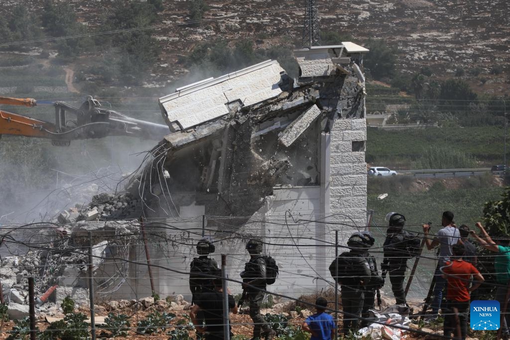 Israeli security forces stand guard as an Israeli bulldozer demolishes a Palestinian house, east of the West Bank city of Hebron, on Aug. 29, 2023.(Photo: Xinhua)