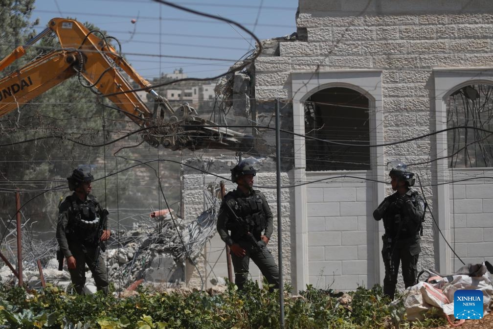 Israeli security forces stand guard as an Israeli bulldozer demolishes a Palestinian house, east of the West Bank city of Hebron, on Aug. 29, 2023.(Photo: Xinhua)