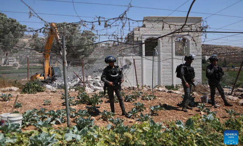 Israeli security forces stand guard as an Israeli bulldozer demolishes a Palestinian house, east of the West Bank city of Hebron, on Aug. 29, 2023.(Photo: Xinhua)