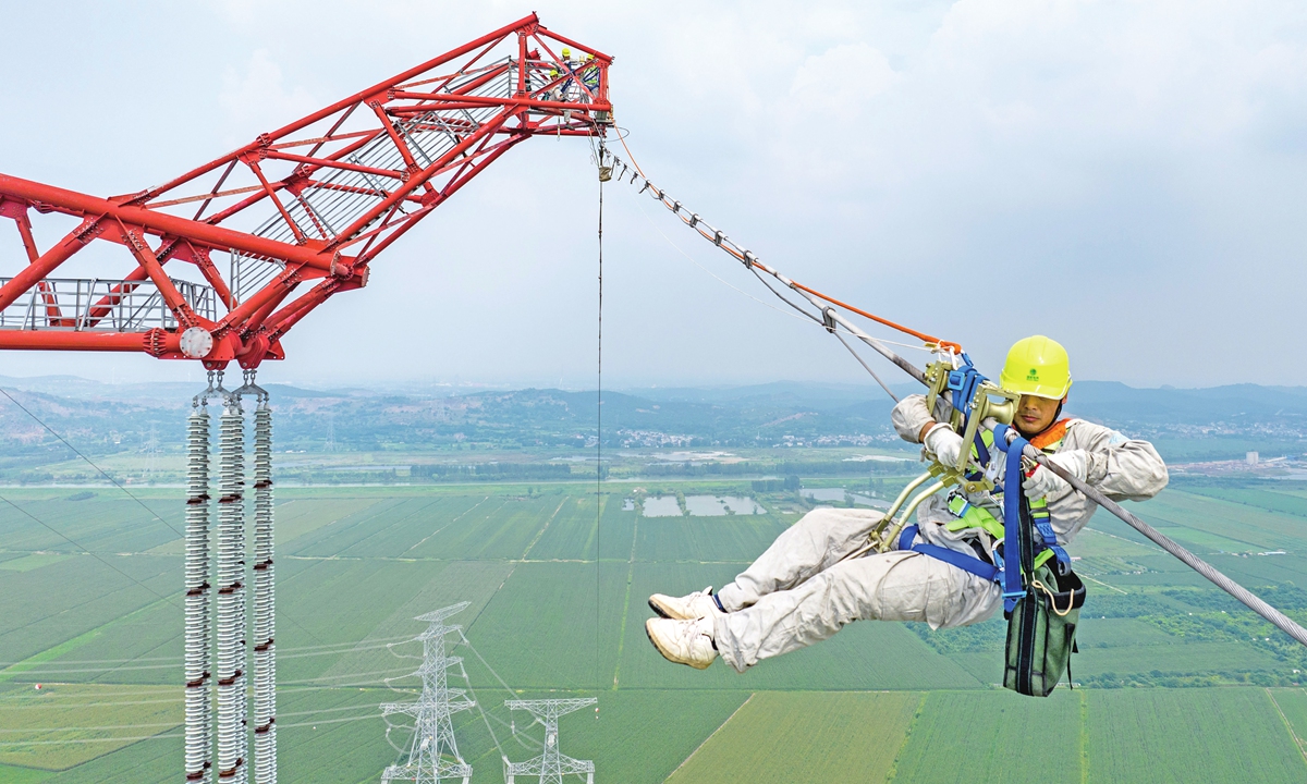A worker from the State Grid Power Supply Company checks and repairs the hidden dangers of the 1000-kilovolt Huaihe River crossing line on August 30, 2023, to ensure the safety of the grid power supply for the Yangtze River Delta region during the peak power usage period. Photo: VCG
