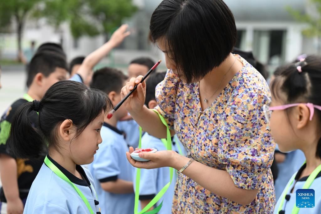 A teacher paints a red dot on the foreheads of children newly admitted to school at Tunxi road primary school in Hefei, east China's Anhui Province, Aug. 30, 2023. The red dot represents the opening of the wisdom eye in China's traditional culture.(Photo: Xinhua)