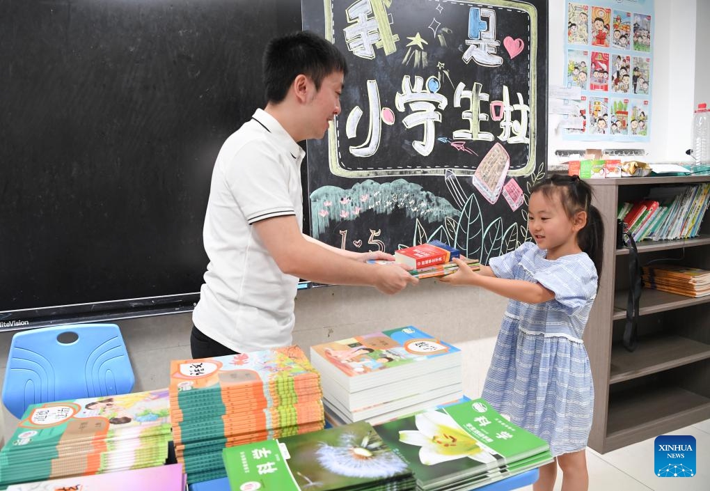 A first grader receives new books from her teacher at the Yajule primary school in Nan'an District of southwest China's Chongqing, Aug. 30, 2023.(Photo: Xinhua)